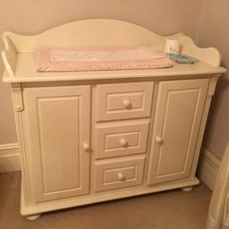 Beautifully made and carved, off-white, very large baby changing table with great hidden storage below. I think made by The White Company.
Has 3 small drawers in middle with extremely smooth runners and 2 single door cupboards with 1 shelf each.
External largest measurements are 1.2metres wide x 54cms deep x 90cms high, but with backing header goes up to 1m12, so protects your wall from grubby hands.
Top surface inside borders for baby mat and wipes and creams etc.. is 1m10 wide x 53cms deep