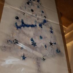 White 6ft Christmas tree for sale with blue and white decorations and lights I've used it for the past few years little crack in a leg but does not effect it at al stands fine