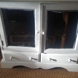 Wooden unit painted white. Has been used for stereo and has a bank of plugs inside cabinet so can 0lug all your electrics in. Glass doors and 2 drawers. Can be upcycled and repainted.. good wood.