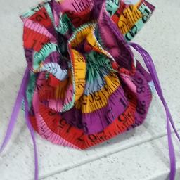 Fabric  made,compact, sewing tidy with draw string closing.
Pockets inside to keep  tape, scissors, cottons etc tidy,  with integral pin cushion in base.
Made in colourful tape measure material. Keep everything neat and in one place. And easy to keep track of.