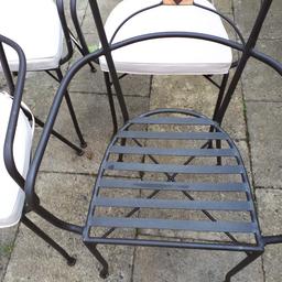 Four brown metal outdoor patio / decking chairs with cream cushions. One chair has a top cap missing as per photo. There is some rust on the back of two chairs as per photo