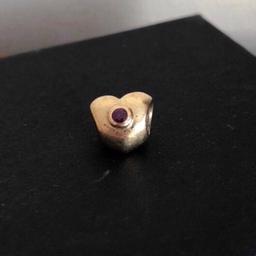 14ct gold with ruby 
Can clearly see hallmark but has been worn 
Retired charm