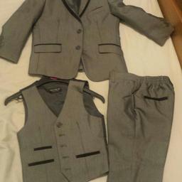 Lovely quality 3pc suit in metallic grey with black hemming around pockets on blazer, waist coat, and trousers. Excellent condition only worn once for wedding. Trousers have elasticated waist with belt straps. Also includes a nice pleating detailed white shirt, making it a 4 piece set. Bought new for £80