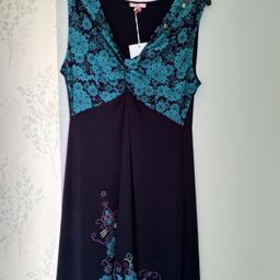 Joe Browns Womens Sleeveless Twist Jersey Dress suitable for any occasion. Size 16, new with tags. It has a lovely teal floral bodice with a twist at the front, dark blue body with an attractive floral print at the bottom. It also has a pink pom-pom fringe at the bottom. Size 16, never worn so still has the tags attached.