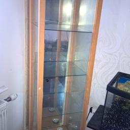 Long glass display cabinet with glass shelf and mirror wall at the back.