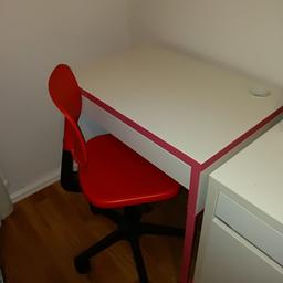 Vit skrivbord med rosa detaljer och rosa/röd stol.