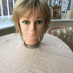 Mousy blond wig with dark roots. By Noriko collection. It is called a Millie wig. The colour is classed as sandal wood. This was £99 and only worn once .lacy netting inside with fasteners to tighten wig. Does not include the head.