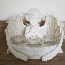 Engel mit ausgebreiteten Flügeln und Kreuz in den Händen. Höhe: 14, Breite: 21, Tiefe: 14 cm, Teelichthalter: Durchmesser 3,7 cm.