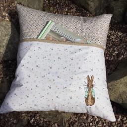 Peter Rabbit reading cushion, ideal for an Easter gift. Book is not included just to show pocket on front of cushion. Zip to back for easy washing. Size 18 x 18 inches.