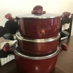 three tefal stock pots in maroon of different sizes