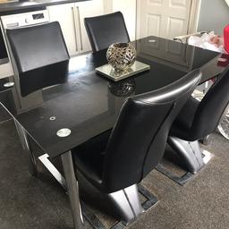 Black glass dining table and four chairs. Has a few little scratches other wise in good condition.