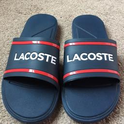Men’s Lacoste sliders authentic 
UK Size 10 Flip-Flops (quite a small fit)
Navy-Blue-Red
L30 118

RRP £28

Used only worn a couple of times as don’t like the feel of the strap.

Bold straps that reflects the very essence of Lacoste

The perfect choice for relaxing on the beach or taking in the sights in style

Lacoste logo on the  outer silhouette 

Synthetic Upper

Rubber outsole