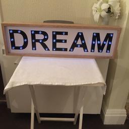 Cream background with black lettering reading dream that lights up. Switch on back. Can be hung or freestanding. Measuring 29 inches long, 8 and a half inches high and 2 inches deep.