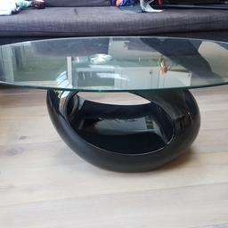 Black and glass coffee table.

This table features a unique oval surface and round hollow gloss black base., which can well accommodate various kinds of accessories or stuffs.

Overall dimensions:
Width : 60 cm
Length: 110cm
Height : 40cm

Collection only from SW18