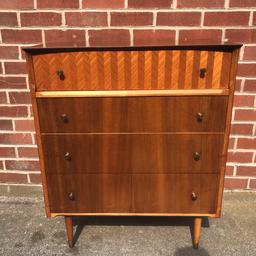 A beautiful teak and rosewood Chest of drawers/ sideboard designed by Peter Hayward for Uniflex furniture Ltd in the 1960s.

The main body and 3 lower drawers are veneered in Brazillian rosewood with the top drawer veneered in Teak arranged in a herringbone parquetry design. Sits on tall tapered legs with brass cup feet.

78cm W x 46cm D x 90cm H

Some marks expected of a used vintage item
Collection Birstall WF17 or delivery available within 50 miles for a small fee