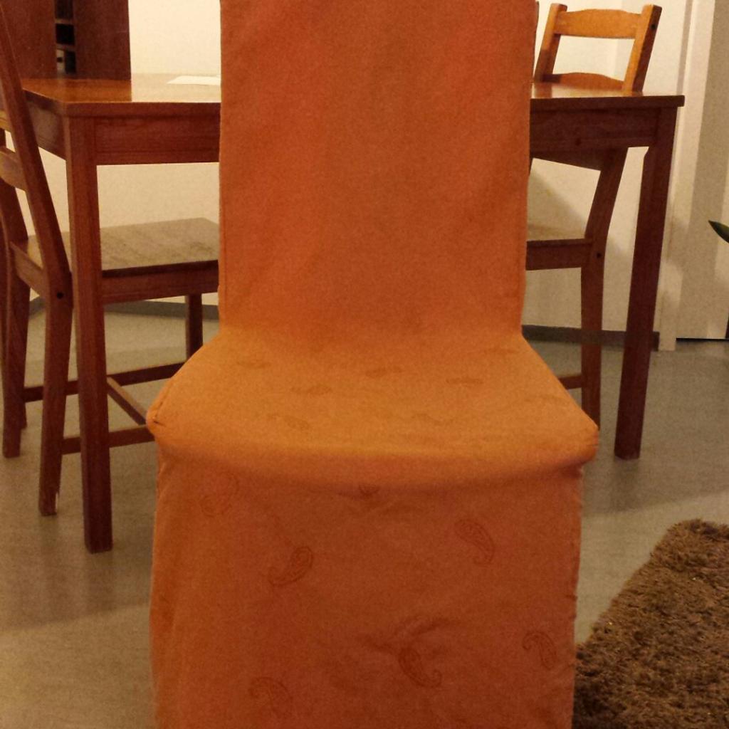 Stuhl aus hellem Holz mit hoher Lehne und Stoffsitzfläche. Schöne orangefarbene Stuhlhusse gehört dazu. Sitzhöhe 47 cm, Sitzbreite 45 cm und Höhe inklusive Lehne 96 cm.