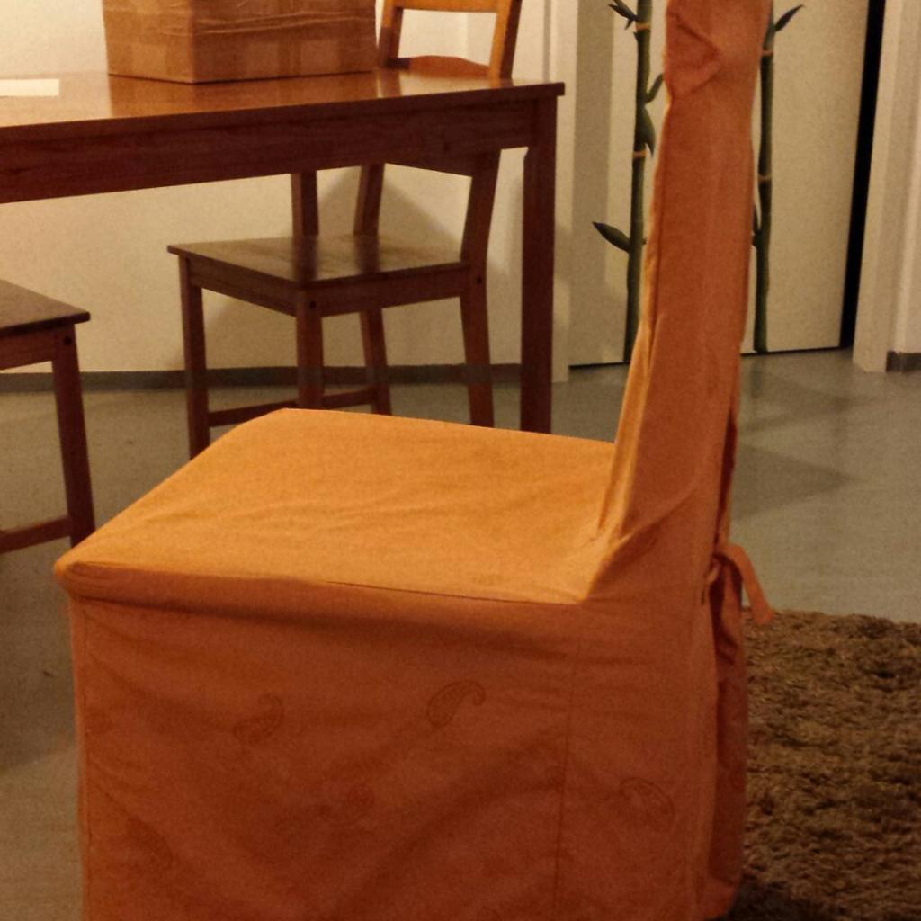 Stuhl aus hellem Holz mit hoher Lehne und Stoffsitzfläche. Schöne orangefarbene Stuhlhusse gehört dazu. Sitzhöhe 47 cm, Sitzbreite 45 cm und Höhe inklusive Lehne 96 cm.