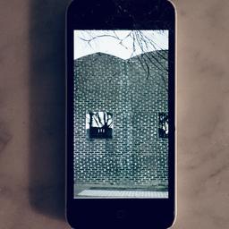 iPhone 5c med 8gb lagringsutrymme. Telefonens frontglas är spräckt som syns på bilden.