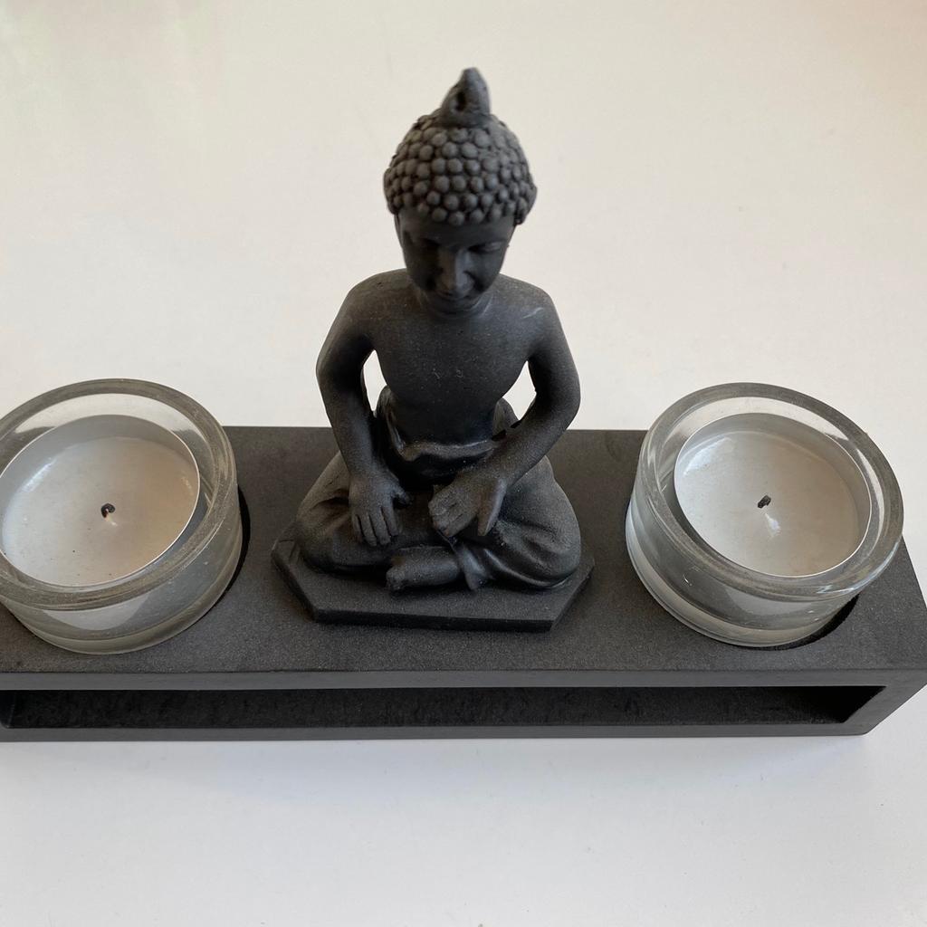 Buddha auf einem Sockel mit 2 Glasbehälter für Teelichter

Maße: 20x14x6 cm