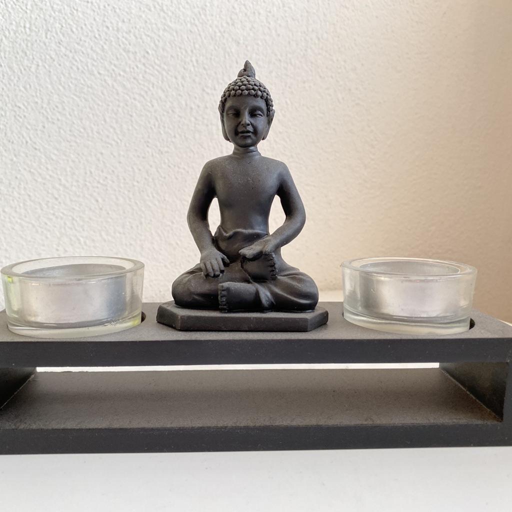 Buddha auf einem Sockel mit 2 Glasbehälter für Teelichter

Maße: 20x14x6 cm
