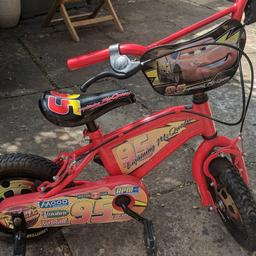 Lightning McQueen bike in red with original plate on handle bars, stickers, trims, chain cover, stabilisers and seat. Good condition, kept in garage although some bolts are starting to rust. It has wheel trims that cover spokes and a fully enclosed chain guard to keep their curious little fingers out of trouble. Stabilisers can be used for confidence and are easily removed once little ones become more capable of balancing. Rubber handles are missing, please see pictures.