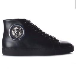 A pair of men’s trainers by versus Versace featuring a sleek hi top silhouette with nine metallic eyelets and a polished metallic lion head badge to the side panels, these luxury hi tops have a round tie and are finished with the versus branding to the sole