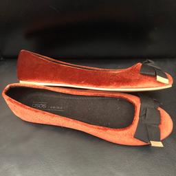 Flat tan suede ballet shoe.with black bow at front.