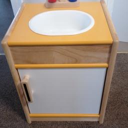 This item is unused but has slight damage in the back (see photo).

Sturdy wooden sink with a tap, front opening door, storage space & removable sink!

A great way to teach children the importance in tidying up after they have finished a meal.

A realistic addition to any play kitchen.

Encourages imaginative play.

Made from high quality, responsibly sourced materials.
Age 3+ years. Height: 52cm, Width: 40cm, Depth: 35cm.