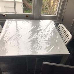 Less then a year old dining table, marble top. In excellent condition no scratches nor marks, with two chairs and two free grey chair cushions. Plus two free table mat in grey including the clear table cover.
