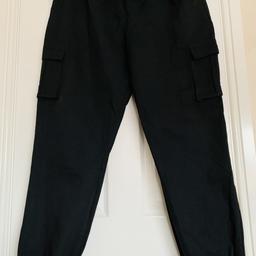 For sale Black women's cargo trousers, with pockets on the sides and elastic bands on the legs, size 16, like new!