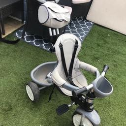Grey kids trike with bag and cup holder and basket had a parent control to manoeuvre and can be mad into a bike when child is bigger