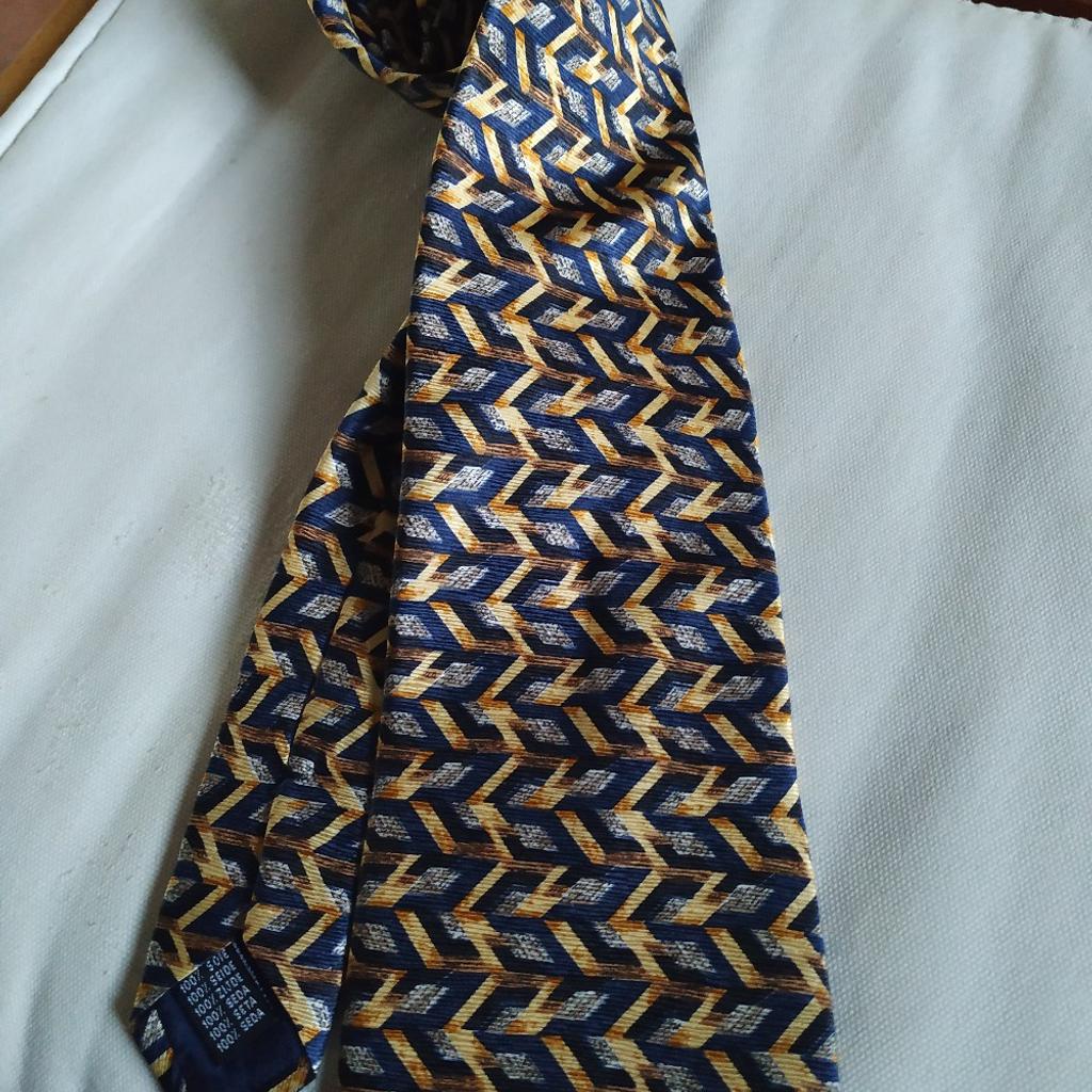 cravatta in pura seta di Ted Lapidus originale, nuova mai usata. ha fondo blu con fantasia in giallo oro e grigio argento. disponibile alla consegna in Roma Eur e alla spedizione