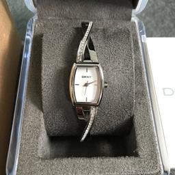 100% genuine DKNY watch in immaculate condition. Only worn once. Full working order, just needs new battery as it has been sat in jewellery box. Comes in original box with guarantee/certificate of authenticity and outer box. Stunning silver coloured watch with sparkly diamanté detail on strap and DKNY branding. Lovely watch, no marks or scratches etc. Strap can easily be made smaller by a jeweller. I can post.