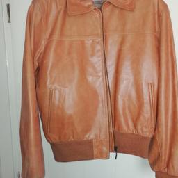 Mens Genuine Tan Leather Bomber Jacket. Size Medium. Ribbed Cuffs and Hem Traps Warmth Inside while Providing a Secure Fit. Full Zip Front Closure. The Jacket Features 2 Side Pockets. The Jacket also has 3 Inside Pockets, One is Zippered, the Other 2 are flap Pockets.