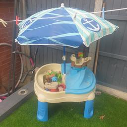 pirate sand and water table with toys and parasol.