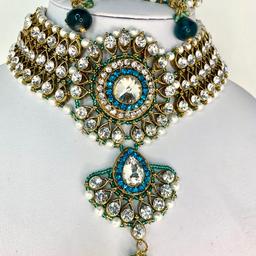 This gorgeous and elegant necklace set will make you turn heads at any occasion.

This Beautiful 4 piece Choker Necklace, Earrings, Side Headpiece & Tika set is perfect for any Occasion. This amazing set is Gold Plated and filled with Gold and Aqua Green Stonework. As the Jewellery is made from Zinc this is a durable material which will not discolour or corrode.
Care Instructions: Keep away from Water, Body Lotions and Perfumes