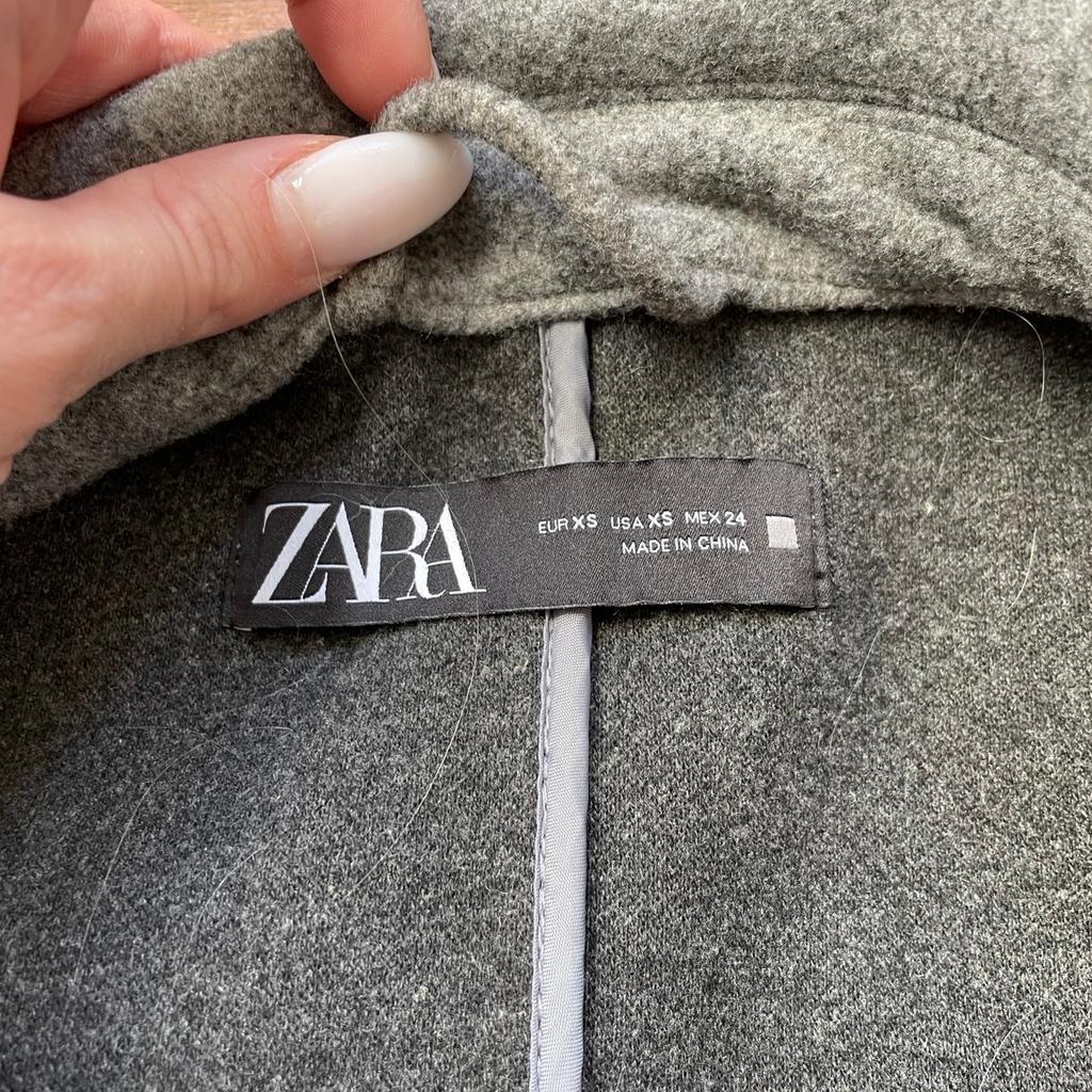 Super erhaltener und kaum getragener Mantel von Zara in einem schönen Dunkelgrau mit Gürtel zum Binden. Minimales Peeling an den Ärmeln etc,jedoch wirklich kaum und absolut noch in einem super Zustand. Größe Xs
