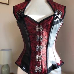 Absolutely stunning brocade steampunk / gothic overbust corset. Heavy red and black brocade with PU trim and thin PU panels on front.

8 steel bones. Collar to back hem length 24"

Metal clip front fasteners, buckle and PU strap detailing over collarbones, Mandarin style collar, 7" modesty panel on back.

Corset size 22" (UK 8-10) (check corset sizing on chart image as they are not based on usual clothing sizes. Recommended to go 2-3" below natural waist measurements)

Cost £110. Worn twice.

this item is heavy (1.5kg) hence P&P cost. This will be sent RM tracked/signed for
