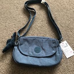Brand new small  Kipling Callia ladies handbag with label still attached with adjustable shoulder strap & zipper closure
Inside: one slip pocket, one zip pocket, one pen slot & a key fob
Outside: zipped back pocket & front Velcro fastening  pocket with furry monkey keychain
Colour: blue jean
Dimensions : H = 7 ins x W = 10 ins x D = 2 ins