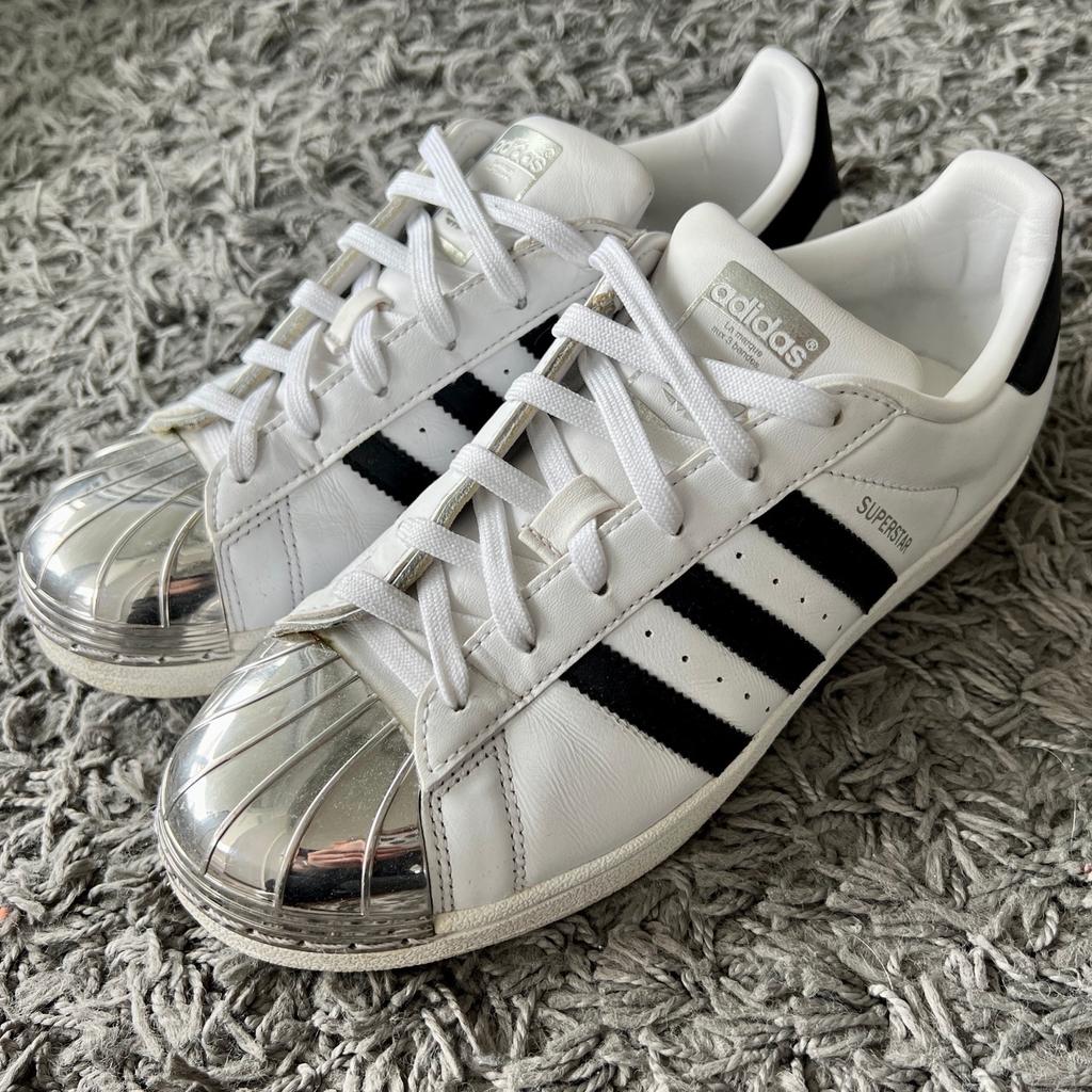 Verkaufe hier ein Paar tolle, ausgefallene Sneaker von Adidas - Modell Superstar mit Metallkappe (Metaltoe) die Schuhe sind schön modern in weiß und schwarz gehalten. Die strahlend, silberne Kappen an der Schuhspitze machte den Sneaker zu einem echten Hingucker. Der Schuh befindet sich in einem top Zstand, da er nur sehr selten getragen wurde. Die Schuhgröße ist eine 38,5.

Bei weiteren Fragen können Sie mir gerne eine Nachricht zukommen lassen.
Die Verpackungs & Versandkosten betragen 5€.

Da es sich hierbei um einen Privatverkauf handelt besteht kein Anspruch auf Garantie, der Umtausch ist ausgeschlossen.
Eine Abholung ist leider nicht möglich.