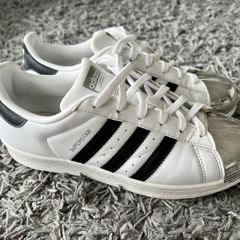 Verkaufe hier ein Paar tolle, ausgefallene Sneaker von Adidas - Modell Superstar mit Metallkappe (Metaltoe) die Schuhe sind schön modern in weiß und schwarz gehalten. Die strahlend, silberne Kappen an der Schuhspitze machte den Sneaker zu einem echten Hingucker. Der Schuh befindet sich in einem top Zstand, da er nur sehr selten getragen wurde. Die Schuhgröße ist eine 38,5.

Bei weiteren Fragen können Sie mir gerne eine Nachricht zukommen lassen.
Die Verpackungs & Versandkosten betragen 5€.

Da es sich hierbei um einen Privatverkauf handelt besteht kein Anspruch auf Garantie, der Umtausch ist ausgeschlossen.
Eine Abholung ist leider nicht möglich.