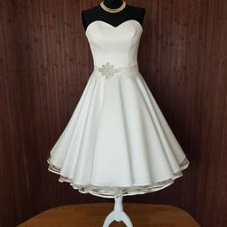 Dieses wunderschöne Petticoat Brautkleid in Ivory ist eine moderne Kombination aus schlichten, eleganten Stoffen und zeitloser Eleganz.

Das knielange Kleid mit einem weitausgestellten Swing Rock sorgt für eine traumhafte Figur und ist absolut edel.

Unglaublich sexy wirkt das Dekolleté mit Herzform-Ausschnitt. Der geschnürte Rücken, sowie der Strass-Bindegürtel ergänzen den magischen Braut-Look stimmig. Dieses wunderschöne Kleid kann mit und ohne Petticoat wunderbar getragen werden. Beides sieht traumhaft schön aus.

Hier haben wir einen 2-lagigen Petticoat mit Satinvolant in Ivory gewählt. Diesen finden Sie in unseren Anzeigen.

Das Kleid wird ohne Petticoat verkauft. Dieser kann bei Bedarf extra erworben werden.
