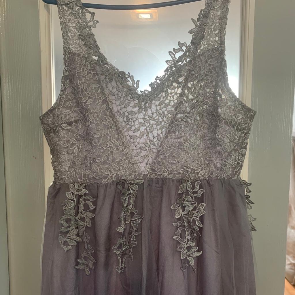 Beautiful silver Prom / Bridesmaids size 12 dress. The dress has two beautiful layers of different material, with a beautiful delicate lace bodice & straps. Very unusual design with the design for the bodice following onto the skirt of the dress. The dress also has a side leg split for that extra glam look. Brand new never worn and an absolute bargain at the asking price.