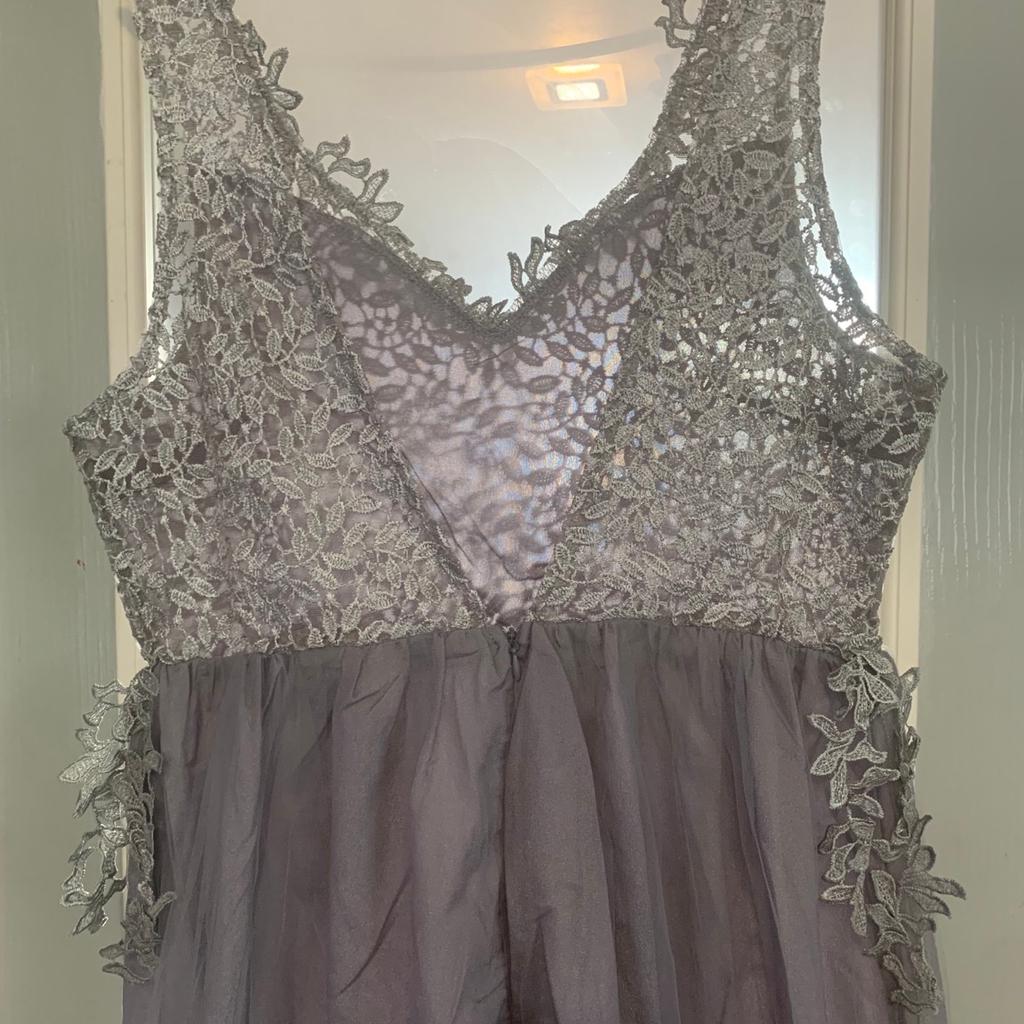 Beautiful silver Prom / Bridesmaids size 12 dress. The dress has two beautiful layers of different material, with a beautiful delicate lace bodice & straps. Very unusual design with the design for the bodice following onto the skirt of the dress. The dress also has a side leg split for that extra glam look. Brand new never worn and an absolute bargain at the asking price.