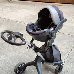 Stokke Kinderwagen V6 mit Babyschale, Regenschutz, Regenschirm Halterung, vorde Tasche in schwarz und zusätzlich die Adapter für verschiedene Babywanne oder Babyschalen. Der Adapter ist kompatibel mit diversen Babyschalen von Maxi-Cosi, Cybex sowie von Nuna.