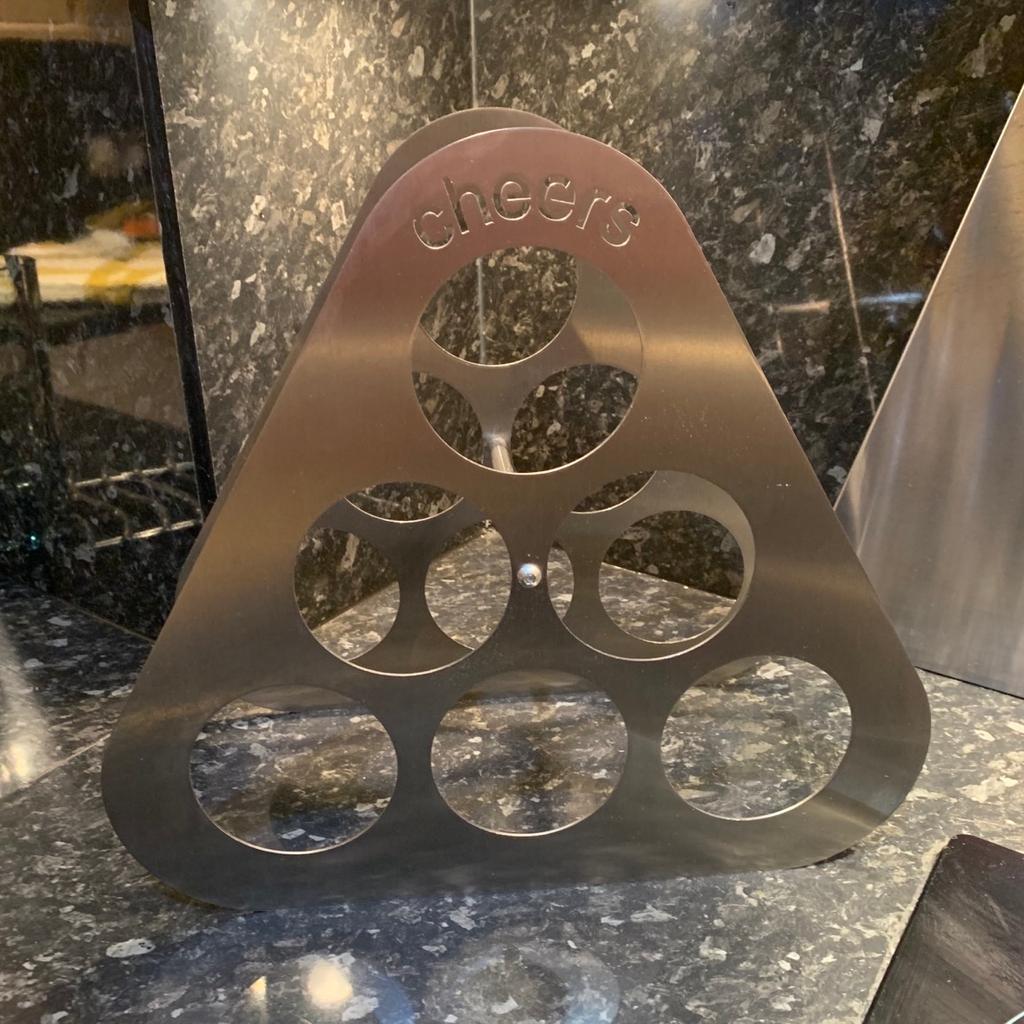 Brushed stainless steel wine rack . Cheers cut out motif at the top. Holds 6 bottles of wine. Looks fab on a kitchen worktop. 38cm wide and 34 cm high. Pick up only. No time wasters or scammers