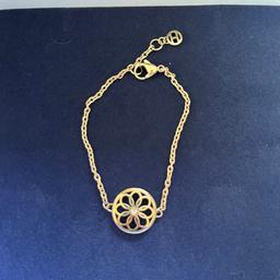 Goldenes Armband von Tommy Hilfiger mit einem großen Ornament in der Mitte, mittig ist noch ein kleiner Stein drin. Das Armband ist längenverstellbar und wird in der Original Schachtel verkauft. Kaum getragen, daher wie neu.