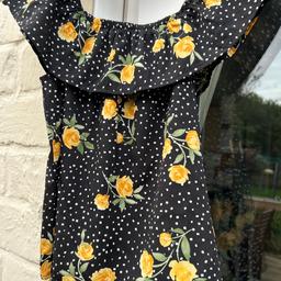 2 piece set with top and shorts, black with white polka dots and yellow flowers. Top: age 10-11, off shoulder elasticated frill. Shorts: age 11-12, elasticated waist