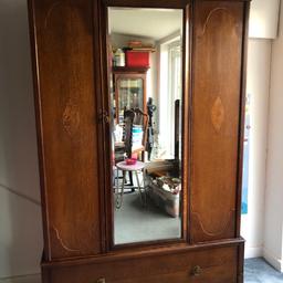 Beautiful solid wood antique wardrobe with inlays and carved border.
With mirror, drawer, rail, hanging rotunda and shelf. Lock in full working order, key included.

Height 192.5 cms
Width 116.5 cms
Depth 45.5 cms

Rail drop 133 cms

Internal drawer dimensions:
Depth 37 cms x height 23.5 cms x width 110 cms

It comes in 2 sections (drawer party sms wardrobe party) for easier transport