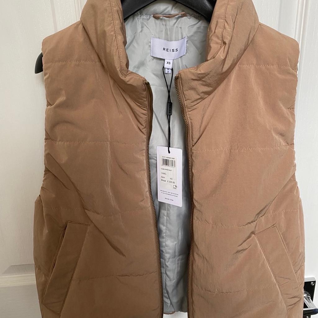 Elodie padded gilet in camel
There is also a concealed hood (pic. 5)
Size: XS (fits uk 8)

Cropped Length
Zip Fastening
Pockets
Composition: 54% Polyamide 46% Polyester
Colour: Camel
Care: Machine Wash
RRP: £225